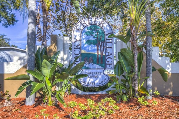 Sign for Rocky Creek Village surrounded by greenery.