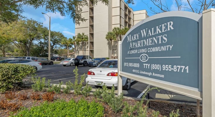 Sign for Mary Walker Senior Apartments with parking area in view