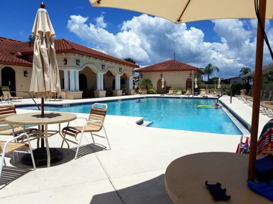 Swimming pool at Village Green Active 55+ Community with lounge chairs and umbrellas.