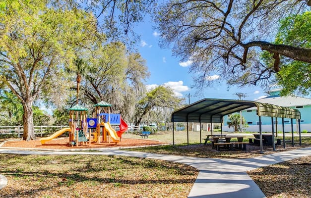 Outdoor playground area with picnic tables and trees