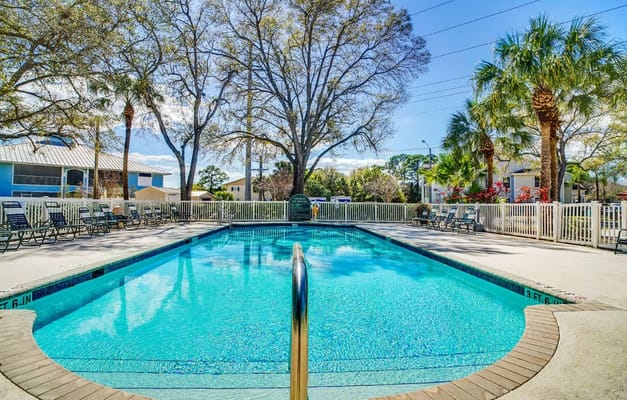 Swimming pool surrounded by lounge chairs and trees
