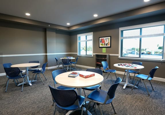 Common area with tables and chairs in a well-lit room