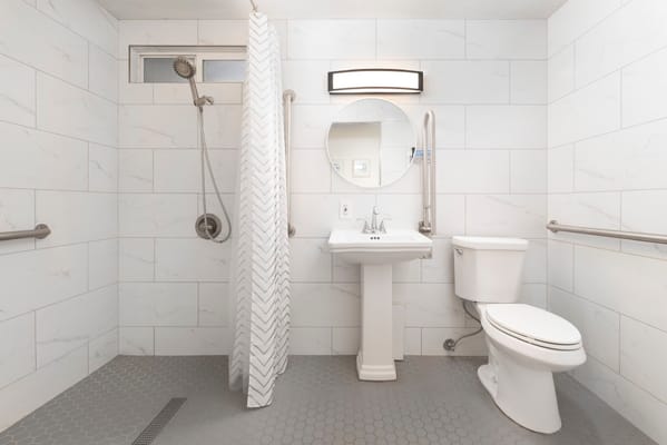Accessible bathroom featuring shower, sink, and toilet