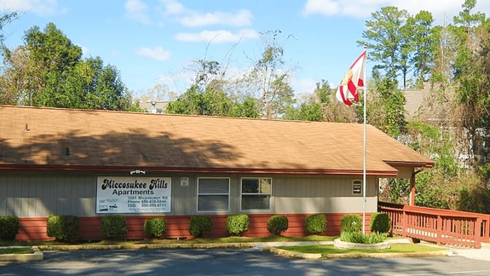 Exterior view of Miccosukee Hills Apartments with flag