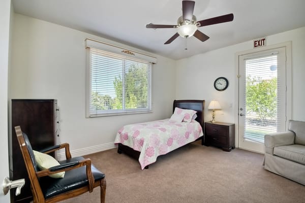 A neatly arranged bedroom with a bed, chair, and window.