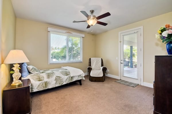 A cozy bedroom featuring a bed, chair, and natural light.