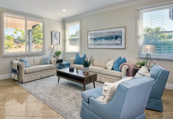 Cozy living room with two sofas and armchairs, large windows, and decorative plants