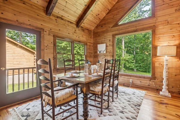Cozy dining area with a wooden table and chairs, surrounded by large windows.