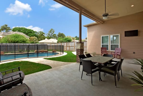 A spacious outdoor patio with seating and a view of the pool.