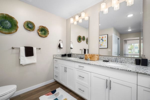 Spacious bathroom with granite countertops and decorative wall art.