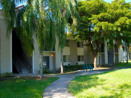 Exterior view of a building with palm trees and a walkway