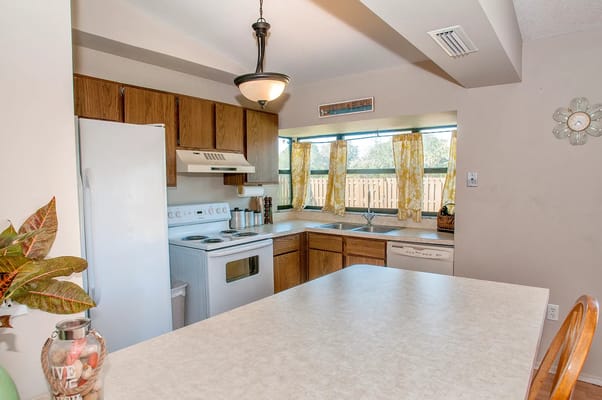 Bright kitchen with wooden cabinets and large windows.