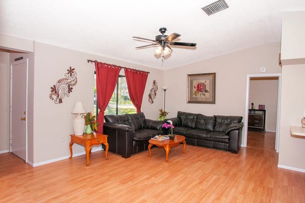 Spacious living room with black leather sofa and wooden accents