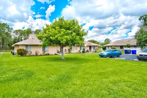 Outdoor view of the assisted living facility with green lawn and trees
