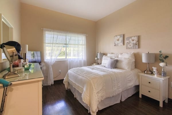A well-lit bedroom with a white bedspread and decorative items.