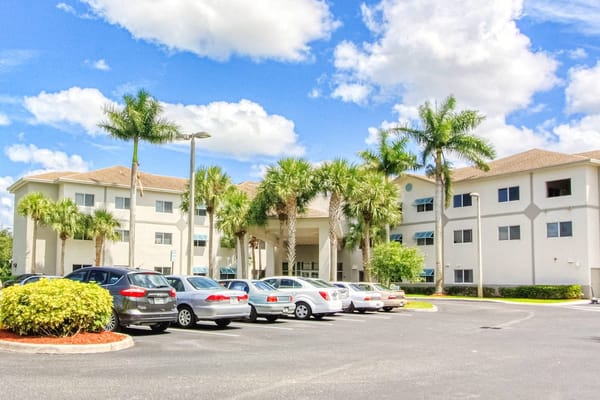 Front view of the Villa Regina senior living facility with palm trees and parking lot