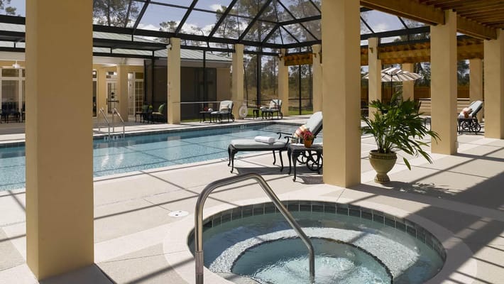 Indoor pool area with lounge chairs and hot tub
