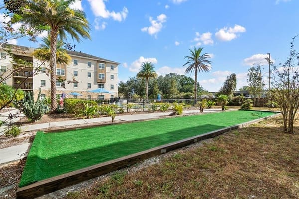 Lush green lawn area with palm trees near the facility.