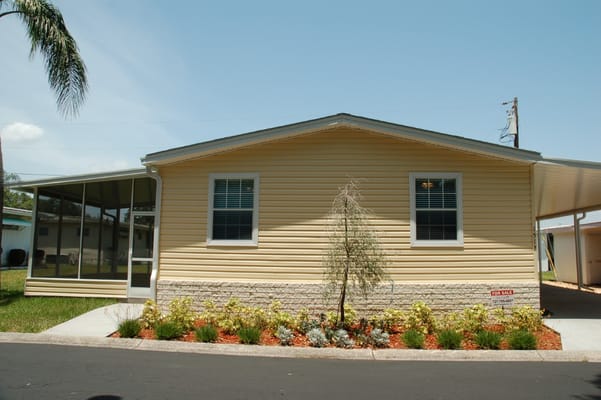 Exterior of a yellow house with landscaping at Twin Lakes.