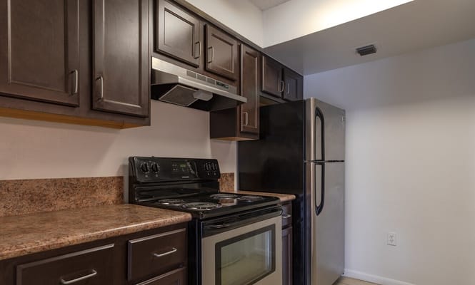 A modern kitchen with dark cabinets and stainless steel appliances.