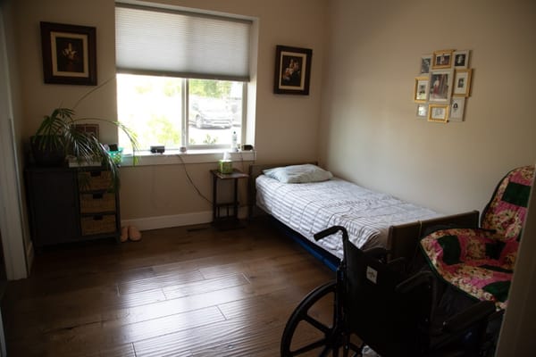 A private resident room with a bed and wheelchair