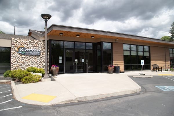 Entrance to Riverview Aquatic Center with flower pots and parking area