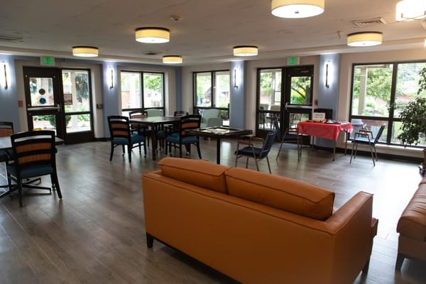 Cozy lounge area with seating and tables in Riverview Retirement Community
