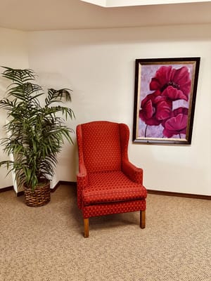 Cozy common area with red chair and floral artwork