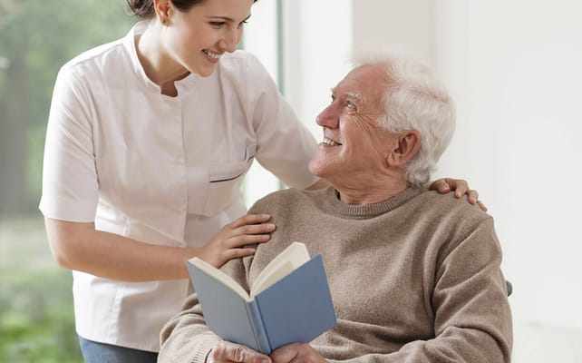 A caregiver and a senior reading together