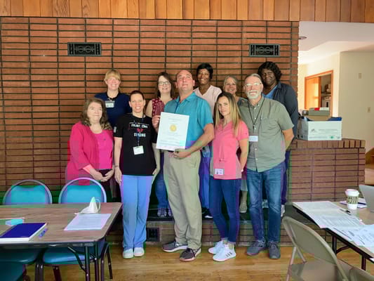 Staff members posing with a recognition certificate