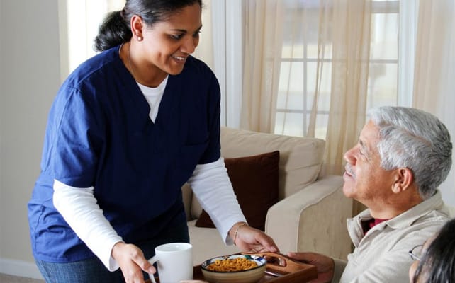 Caregiver serving food to a resident in a cozy room