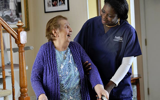 A caregiver assisting a laughing resident indoors