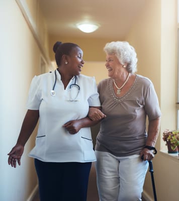 Staff member assisting a smiling resident in a hallway