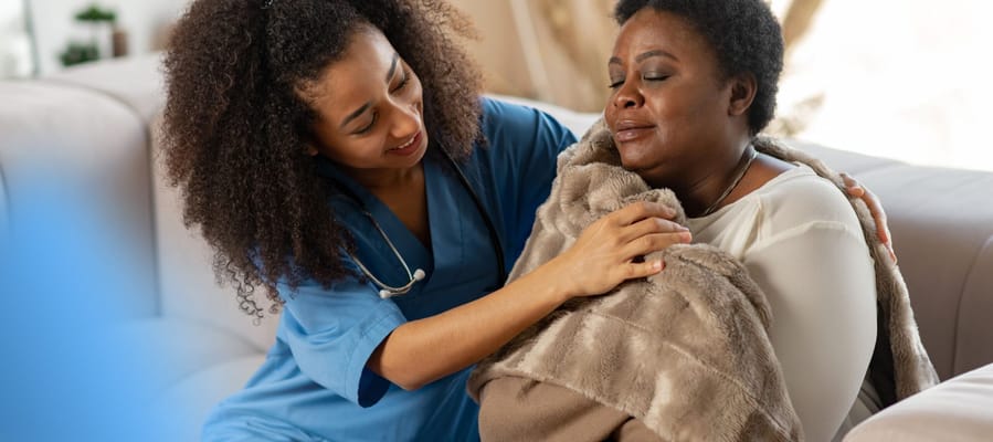 Caregiver comforting resident with a blanket
