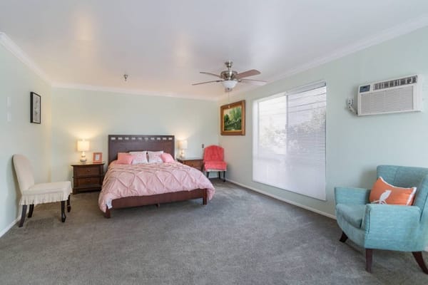 Brightly decorated private resident room with bed and seating