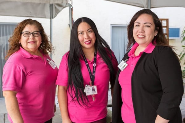 Three staff members posing in pink uniforms