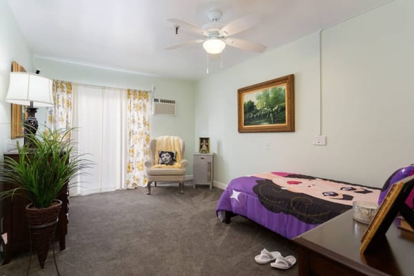 A cozy resident room with a bed and chair