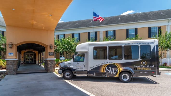 Parking area and entrance of Sweet Water Grand The Bridges assisted living facility with shuttle bus