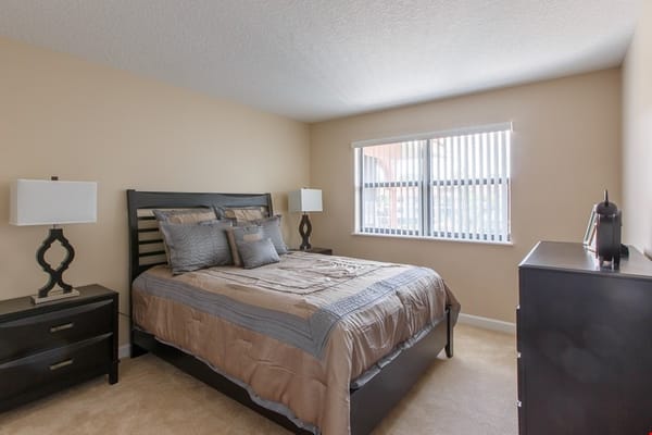 A modern bedroom with a queen-sized bed, two lamps, and a dresser.