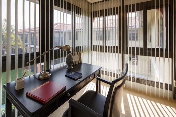 A well-lit office space with a desk, lamp, and large windows.