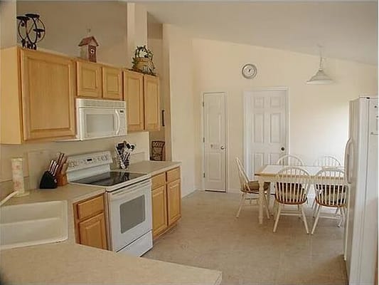 Kitchen space with wooden cabinets, stove, and dining table.