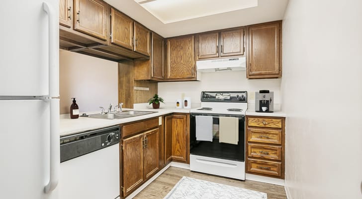 A view of a compact kitchen with wooden cabinets and appliances.
