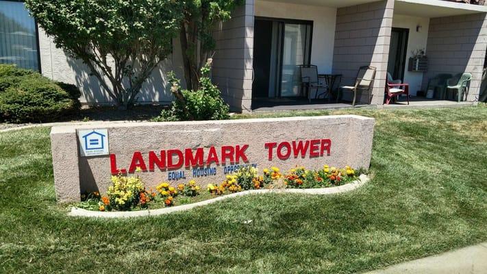 Sign for Landmark Tower Apartments with flowers and greenery