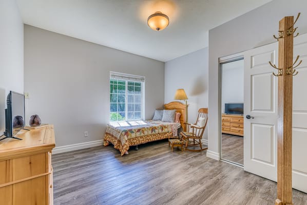 A cozy private resident room with a bed and a chair