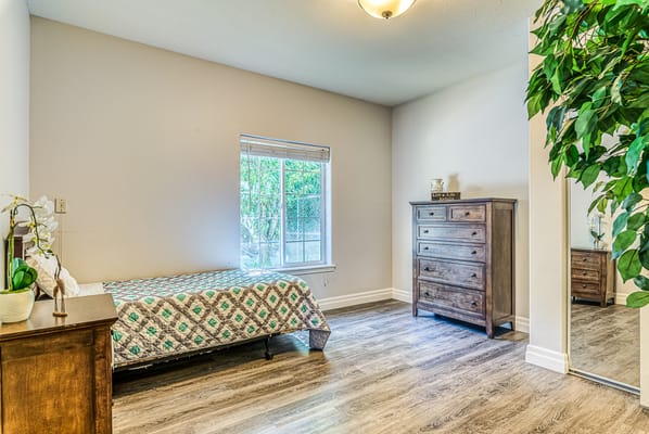 Bright, inviting private resident room with a bed and dresser