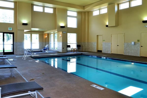 Indoor pool area with lounge chairs and natural light