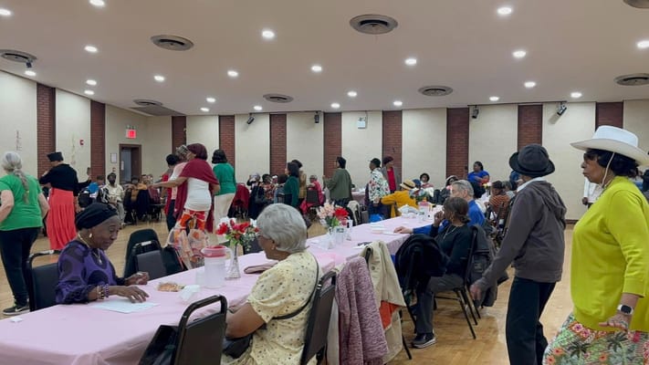 Seniors enjoying a lively community gathering with tables set up for a meal.