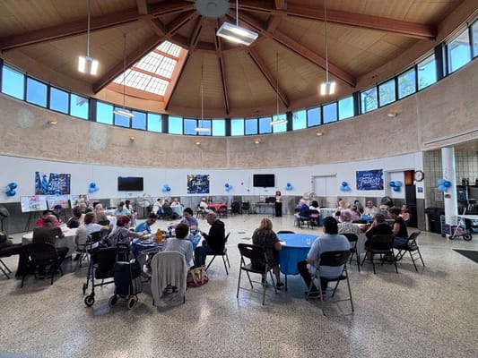 Seniors gathered around tables celebrating Father's Day in a well-lit hall.