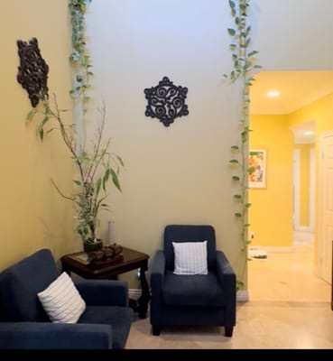 A cozy living room with blue chairs and decorative wall features.