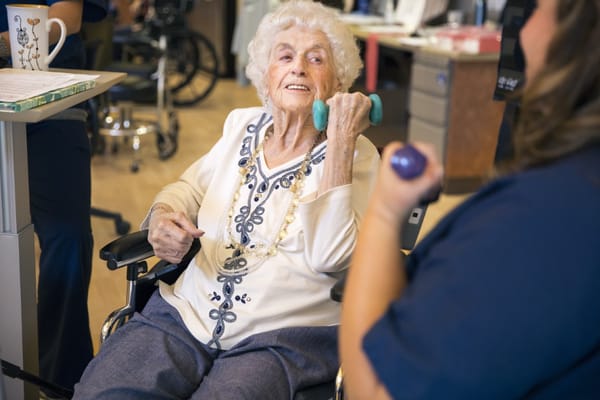 Senior woman in a wheelchair participating in an exercise session with weights.